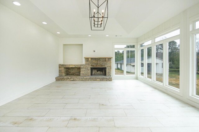 unfurnished sunroom featuring a fireplace, a chandelier, and a tray ceiling