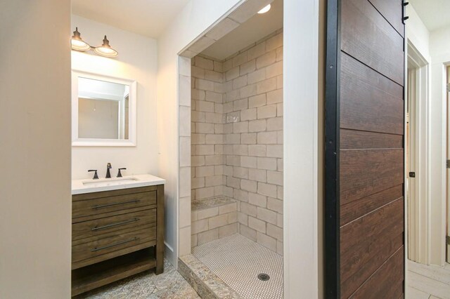 bathroom with a tile shower and vanity