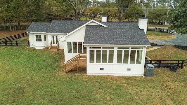 back of house with central air condition unit, a sunroom, and a lawn