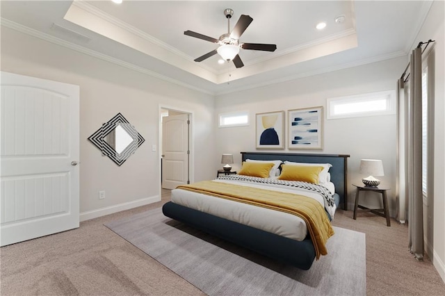 carpeted bedroom with a tray ceiling, multiple windows, ceiling fan, and ornamental molding