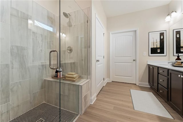 bathroom with hardwood / wood-style floors, vanity, and a shower with shower door