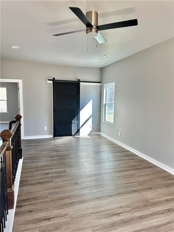 interior space with hardwood / wood-style floors, plenty of natural light, a barn door, and ceiling fan