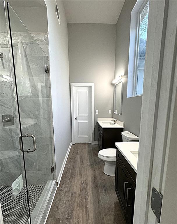 bathroom featuring hardwood / wood-style flooring, vanity, toilet, and a shower with shower door