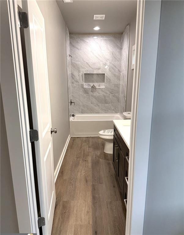 full bathroom featuring hardwood / wood-style flooring, vanity, toilet, and tiled shower / bath combo