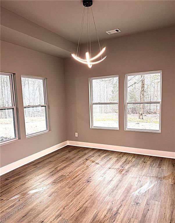 empty room featuring hardwood / wood-style floors and a notable chandelier