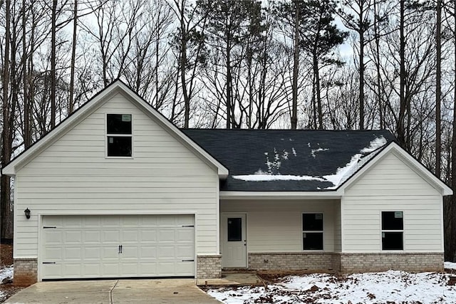 view of front of property featuring a garage, concrete driveway, and brick siding