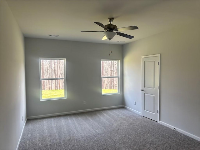 carpeted empty room featuring ceiling fan, visible vents, and baseboards