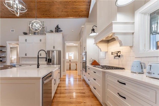 kitchen with white cabinets, pendant lighting, stainless steel appliances, and light countertops