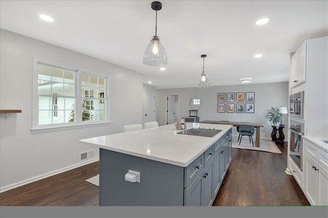 kitchen with a kitchen island with sink, decorative light fixtures, stainless steel appliances, and white cabinets