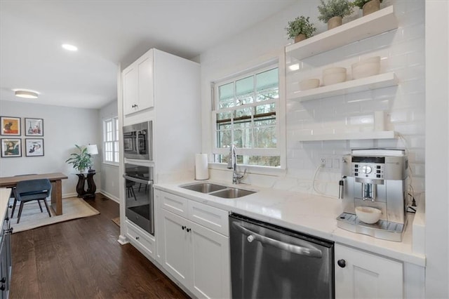 kitchen featuring sink, light stone counters, dark hardwood / wood-style floors, stainless steel appliances, and white cabinets