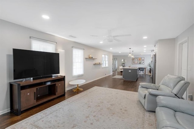 living room featuring dark wood-type flooring and ceiling fan