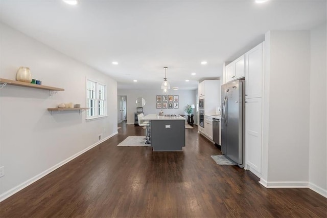 kitchen with a breakfast bar, appliances with stainless steel finishes, a kitchen island, pendant lighting, and white cabinets