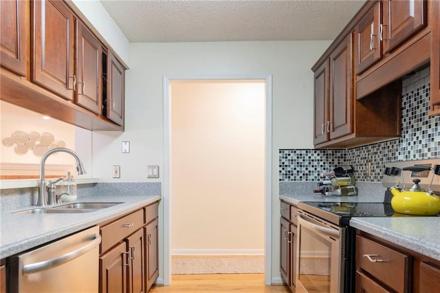 kitchen with light countertops, appliances with stainless steel finishes, a sink, and tasteful backsplash