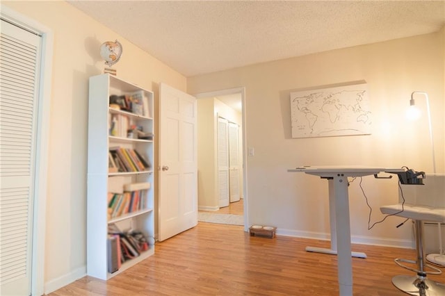 interior space with a textured ceiling, light wood-style flooring, and baseboards