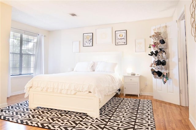 bedroom featuring light wood-style floors, visible vents, and baseboards