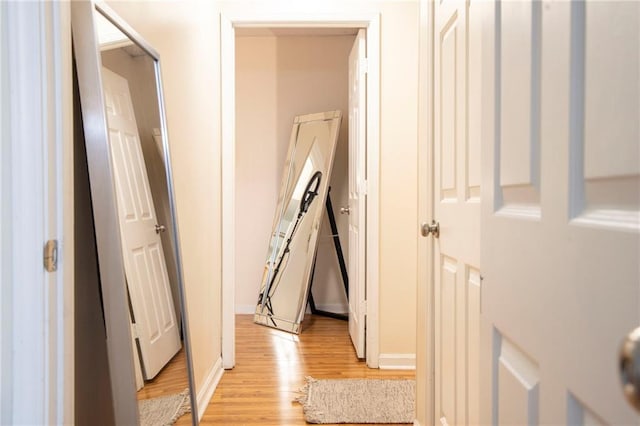 corridor with light wood-style flooring and baseboards