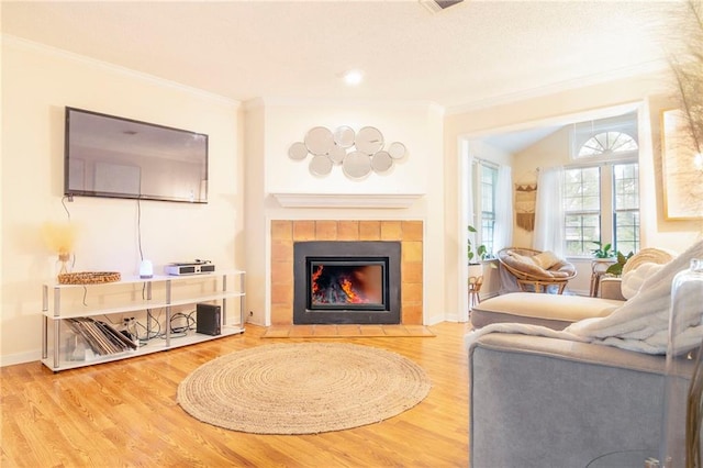 sitting room featuring ornamental molding, a tile fireplace, baseboards, and wood finished floors