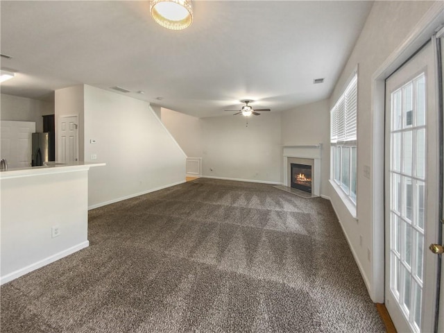 unfurnished living room with dark colored carpet and ceiling fan