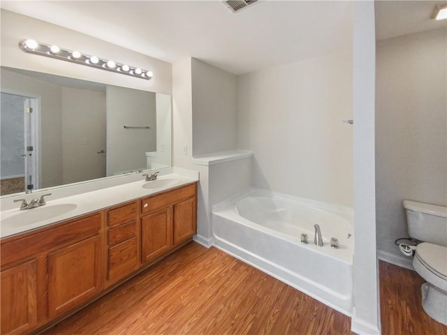 bathroom featuring a tub, hardwood / wood-style flooring, toilet, and vanity