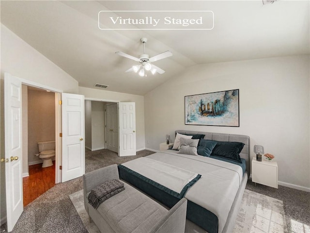 bedroom featuring ceiling fan, vaulted ceiling, ensuite bath, and carpet flooring