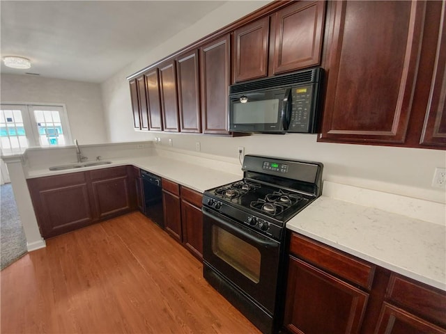 kitchen featuring black appliances, light hardwood / wood-style floors, french doors, and sink