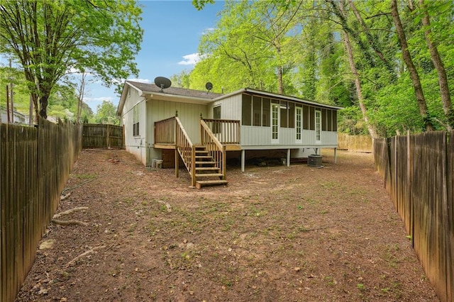 rear view of property featuring a deck, a fenced backyard, a sunroom, and central AC unit