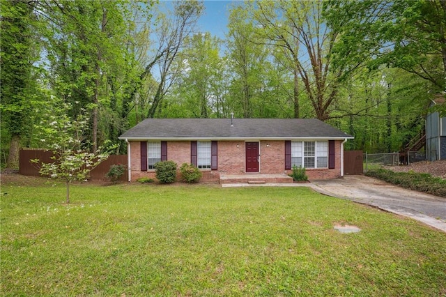 ranch-style house with driveway, fence, a front lawn, and brick siding