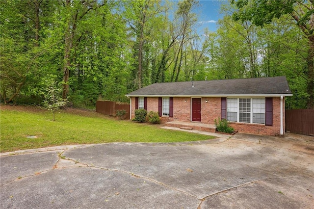 ranch-style house with driveway, fence, a front lawn, and brick siding