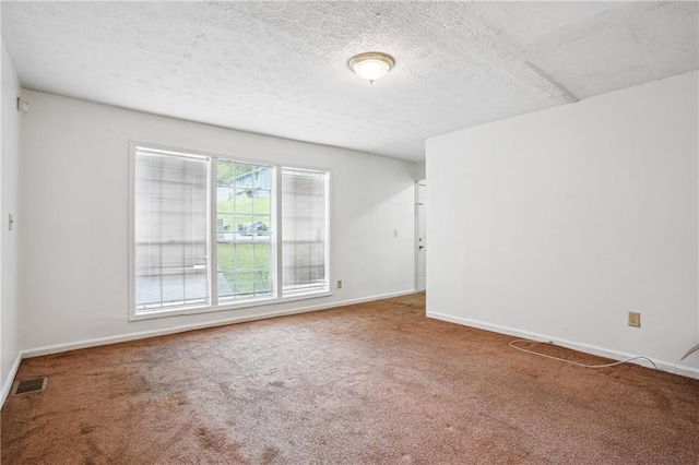 unfurnished room featuring a textured ceiling, carpet flooring, baseboards, and visible vents