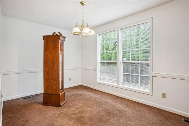 spare room with baseboards, a notable chandelier, visible vents, and carpet floors
