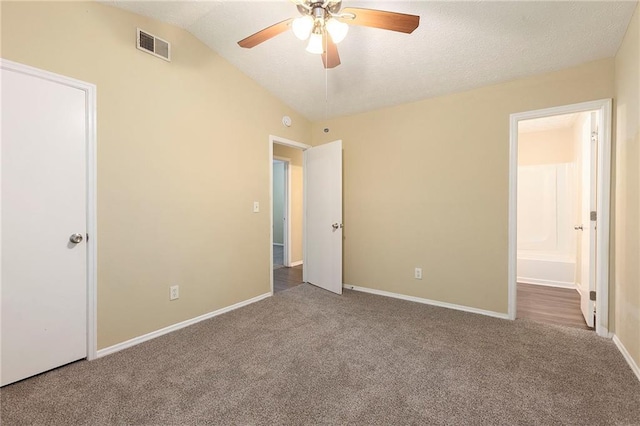 unfurnished bedroom with ceiling fan, carpet flooring, vaulted ceiling, and ensuite bath