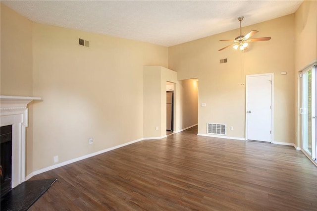 unfurnished living room with dark wood-type flooring, a textured ceiling, high vaulted ceiling, and ceiling fan