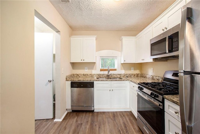 kitchen with sink, appliances with stainless steel finishes, a textured ceiling, and white cabinetry