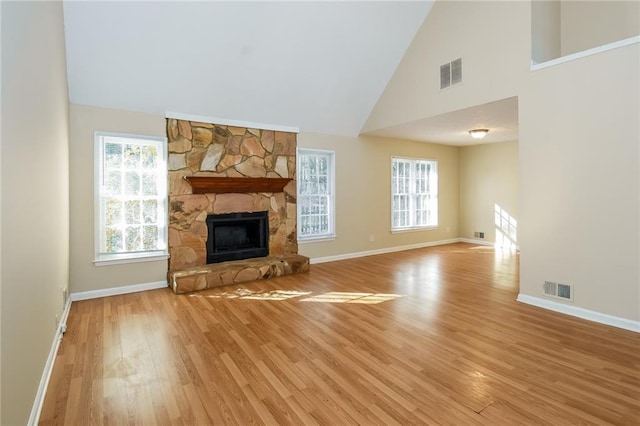 unfurnished living room with light hardwood / wood-style flooring, a fireplace, and high vaulted ceiling