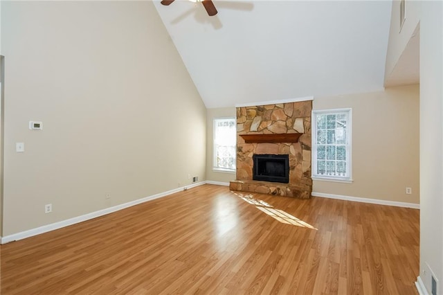 unfurnished living room with high vaulted ceiling, a wealth of natural light, a fireplace, and light hardwood / wood-style flooring