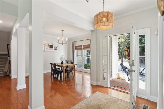 entryway with crown molding, hardwood / wood-style floors, and a chandelier