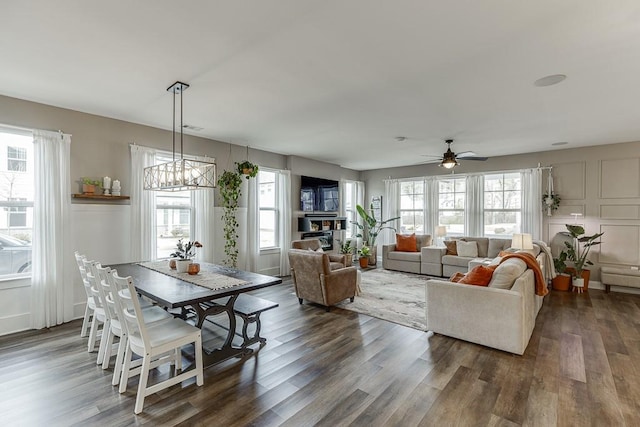 dining space with dark hardwood / wood-style flooring, ceiling fan with notable chandelier, and a wealth of natural light