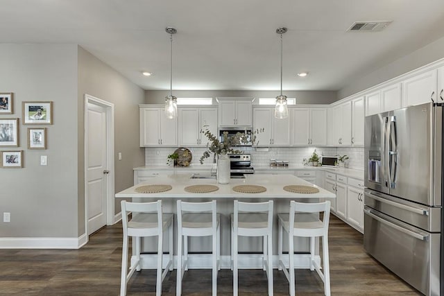 kitchen with appliances with stainless steel finishes, decorative light fixtures, and white cabinets