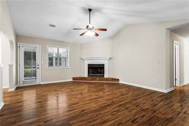 unfurnished living room featuring a brick fireplace, dark hardwood / wood-style floors, lofted ceiling, and ceiling fan