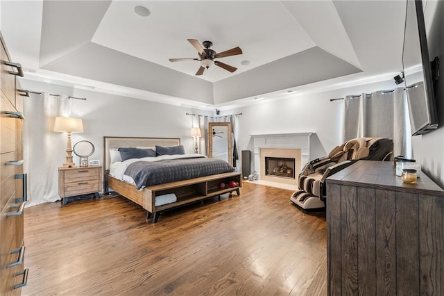 435 Ruby Forest Pkwy, Suwanee, GA 30024 - bedroom featuring a tray ceiling, wood finished floors, a fireplace, and ceiling fan