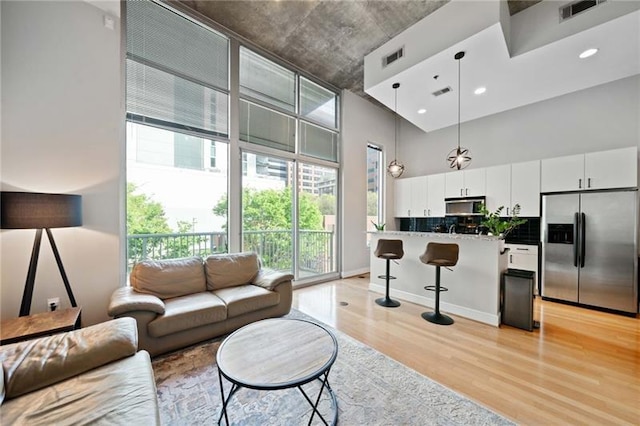 44 Peachtree Pl NW Unit 528, Atlanta, GA 30309 - living room with visible vents, plenty of natural light, light wood-style flooring, and a high ceiling