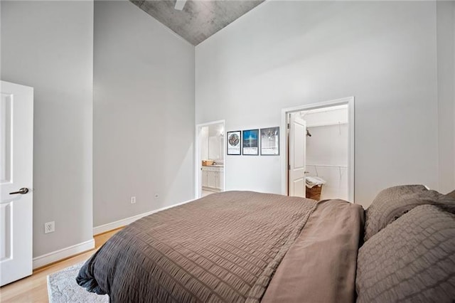 44 Peachtree Pl NW Unit 528, Atlanta, GA 30309 - bedroom featuring light wood-type flooring, baseboards, a towering ceiling, and connected bathroom