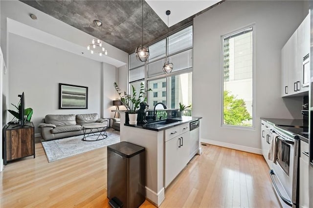 44 Peachtree Pl NW Unit 528, Atlanta, GA 30309 - kitchen featuring dark countertops, a sink, stainless steel appliances, light wood-style flooring, and white cabinetry