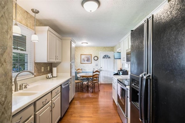 3359 Villa Ln, Douglasville, GA 30135 - kitchen featuring appliances with stainless steel finishes, wood finished floors, light countertops, pendant lighting, and a textured ceiling