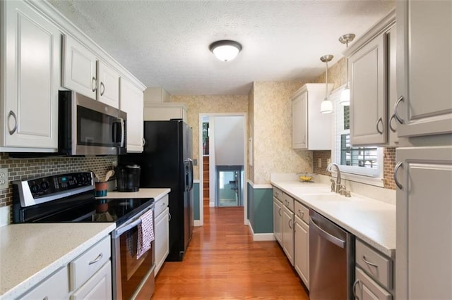 3359 Villa Ln, Douglasville, GA 30135 - kitchen with appliances with stainless steel finishes, light wood-style flooring, light countertops, decorative backsplash, and a textured ceiling
