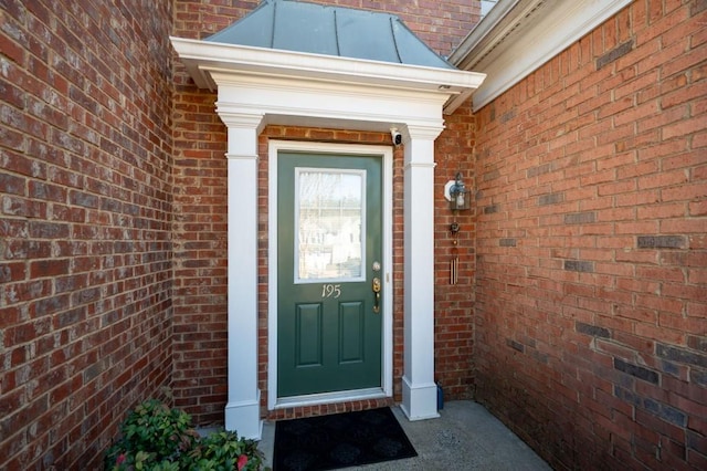 entrance to property featuring a standing seam roof and brick siding