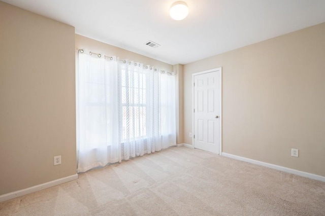 empty room featuring light carpet, baseboards, and visible vents