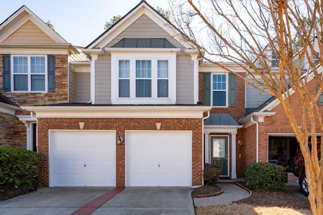 multi unit property with a garage, concrete driveway, brick siding, and a standing seam roof