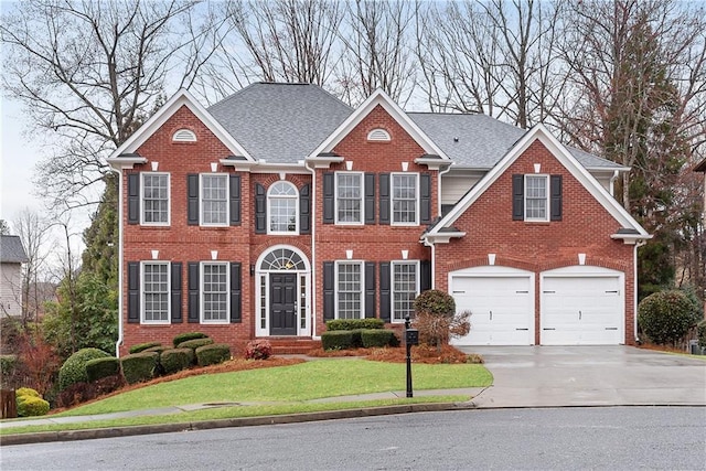 colonial home featuring brick siding, driveway, an attached garage, and a front yard