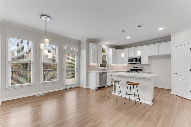 kitchen featuring tasteful backsplash, appliances with stainless steel finishes, light countertops, and ornamental molding